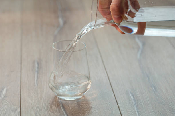 refrigerante ou água sendo derramado em vidro liso com gelo - pouring water carafe glass - fotografias e filmes do acervo