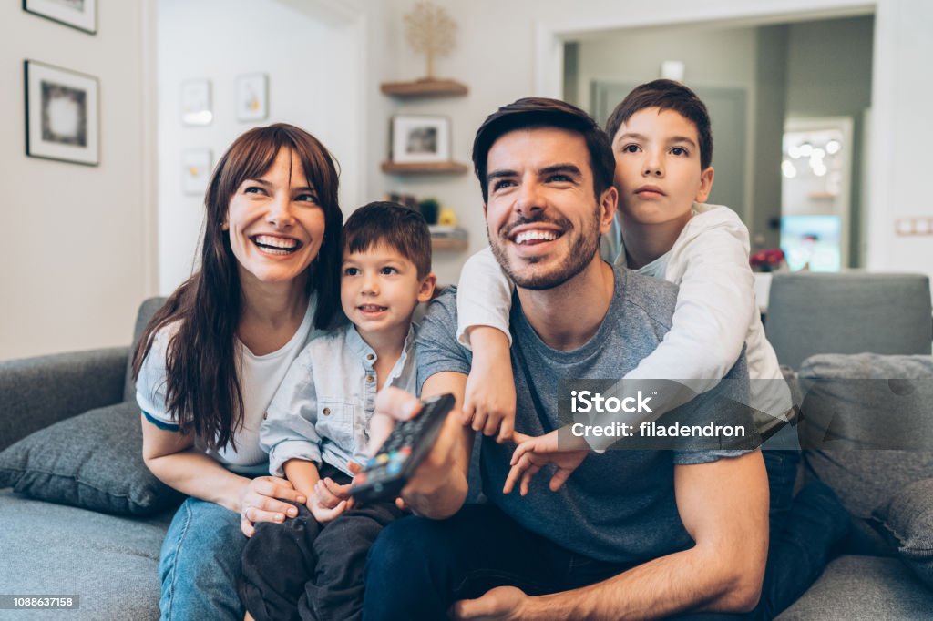 Family watching television Family relaxing at home watching television together Family Stock Photo
