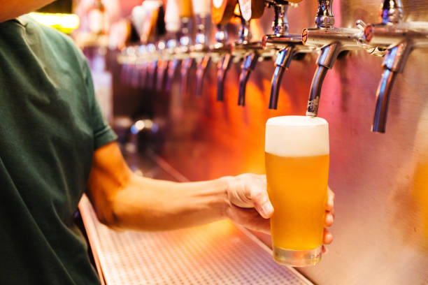 男注ぐビール クラフト ビールは、泡と凍ったガラスにタップします。選択と集中。アルコールのコンセプトです。ビンテージ スタイルです。ビール クラフト。バーのテーブル。鋼のタップ - beer beer glass drink alcohol ストックフォトと画像