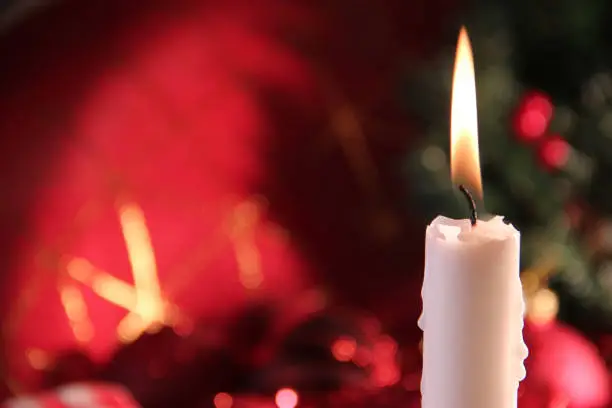 A white lit christmas candle against a christmas background