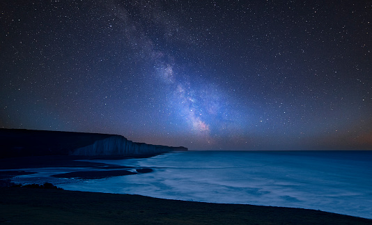 Stunning vibrant Milky Way composite image over landscape of Seven Sisters chalk cliffs in England