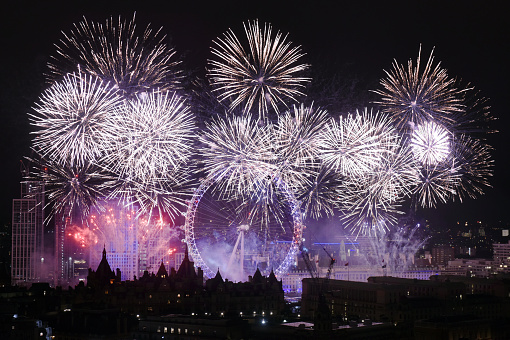 Midnight is celebrated along the River Thames in London with a spectacular and colourful  firework display. View over city rooftops