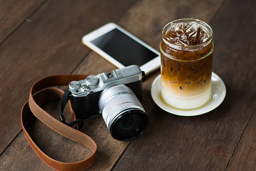 Iced coffee and the camera on a wooden table