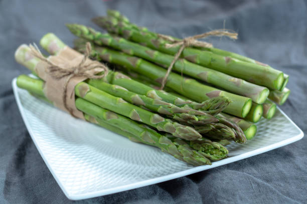 istock Fresh raw green asparagus vegetable on white board, close up 1088688592
