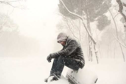 Pensive man sitting on bench snowy day