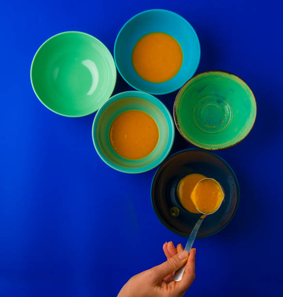 pouring pumpkin soup into a blue bowl, top view