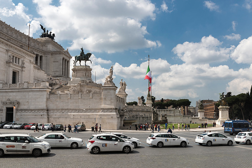 Rome, Italy - April 7, 2017: The Monumento Nazionale a Vittorio Emanuele II (National Monument to Victor Emmanuel II) or Altare della Patria (Altar of the Motherland) or 'Il Vittoriano' located between the Piazza Venezia and the Capitoline Hill in Rome, Italy. Many people can be seen visiting the monument. In the street in the foreground are many taxicabs.