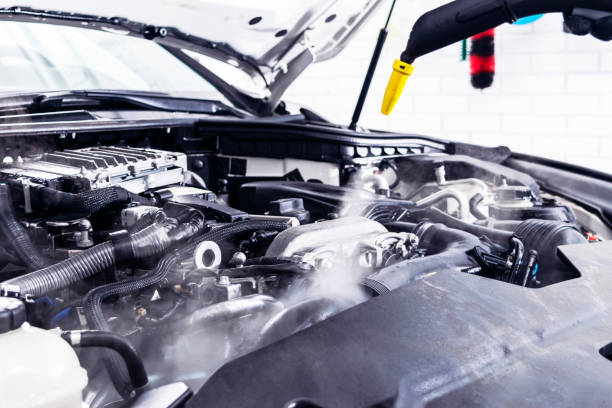 istock Car detailing. Car washing cleaning engine. Cleaning car engine using hot steam. Hot steam engine washing. Soft lighting. Car wash station worker cleaning vehicle. Car wash concept 1088745310