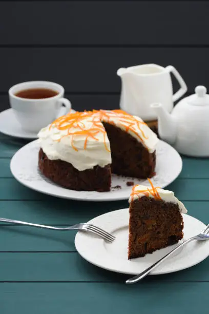 Black tea and chocolate cake with cream cheese and orange peel on dark blue background vertical