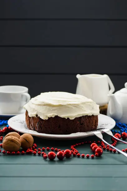 Traditional fruit cake minimalist style. Tasty chocolate cake with cream cheese and white teaware on dark blue background copyspace