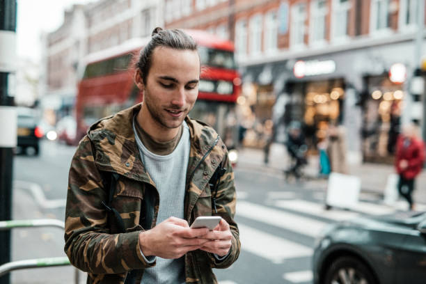 istock Cheerful guy walking in the street and using smart phone 1088756254