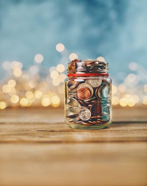 brightly lit donation money jar filled with coins - vertical bright brightly lit vibrant color imagens e fotografias de stock