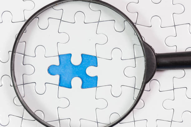 istock Pieces of a puzzle magnifying glass, close up. Conceptual image of connection, solution and business strategy. 1088759542
