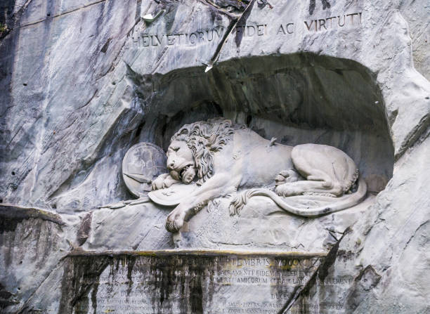 Lucerne, Switzerland-May 23, 2016-The Lion of Lucerne is monument carved in 1820 to honor the Swiss soldiers who died defending King Louis the 16th during the French Revolution  Designed by Bertel Thorvaldsen it is   carved on the face of stone cliff with the pond in the foreground. The artist, irate because of non payment carved the outline of a pig around the lion.