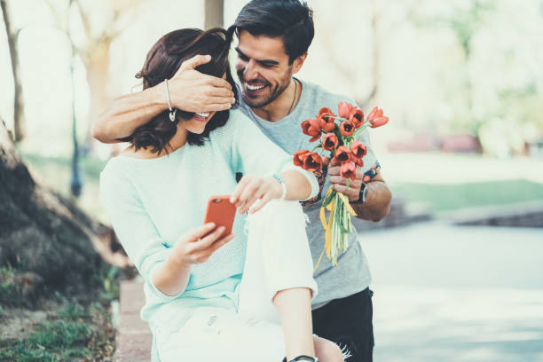 giovane sorprende la sua ragazza con bouquet di tulipani - attività romantica foto e immagini stock