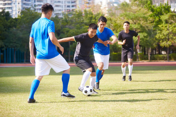 young asian adult men playing soccer a group of young asian soccer football player playing on outdoor court. offense sporting position photos stock pictures, royalty-free photos & images