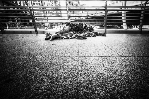 Poor homeless beggar laying and sleeping on pathway in black and white tone