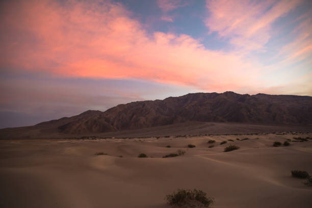 оранжевый и розовый закат облака над песчаными дюнами и горы в долине смерти национальный парк - sand dune sand orange california стоковые фото и изображения