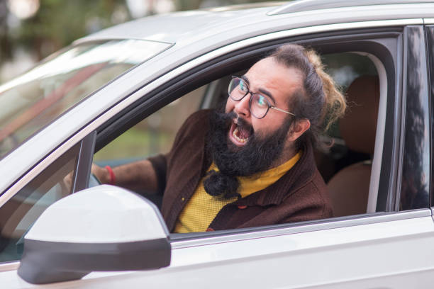 Angry man behind the wheel demonstrating road rage Side profile angry hipster man driver evil stock pictures, royalty-free photos & images
