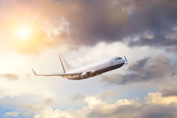 Photo of airplane flying away in to sky high altitude above the strom clouds