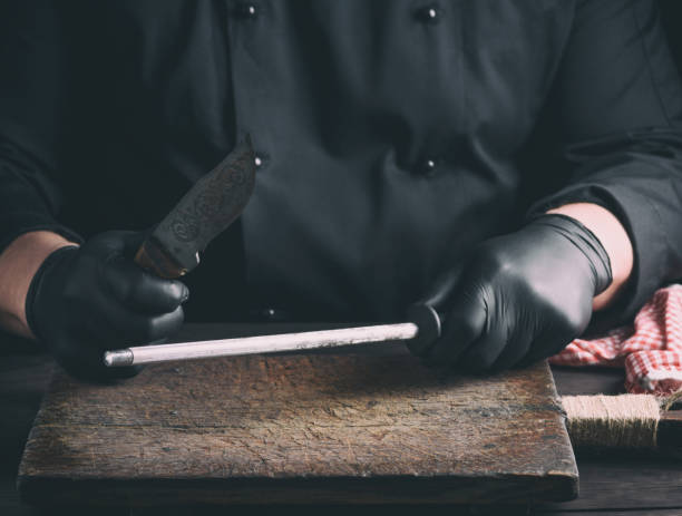 istock cook in black latex gloves sharpens a knife over a wooden table 1088842492