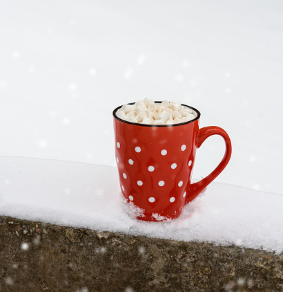 red ceramic mug with hot chocolate and marshmallow, close up