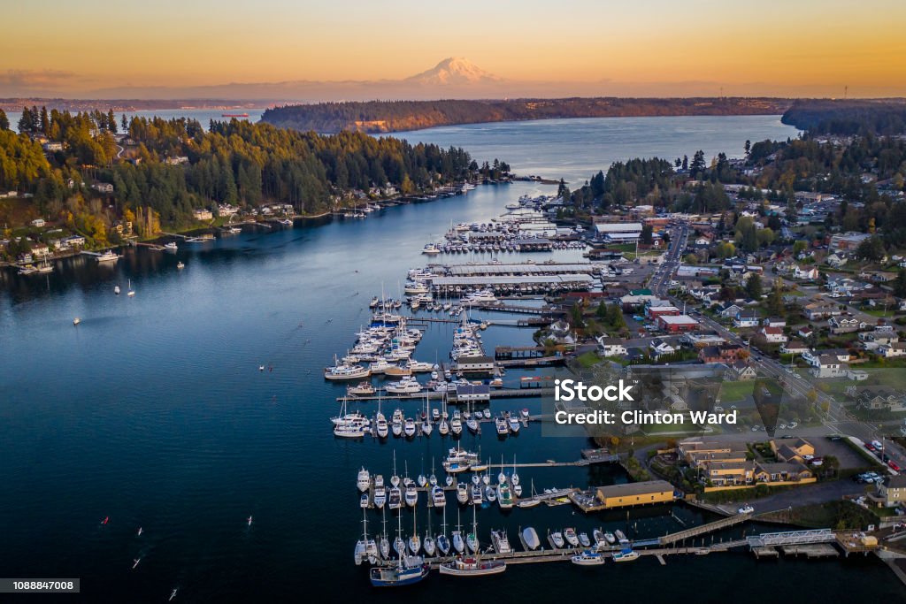 Orange Sunset Glow Over Gig Harbor Washington Aerial A drone view of boats in Gig Harbor Washington at sunset with Mt Rainier Washington State Stock Photo