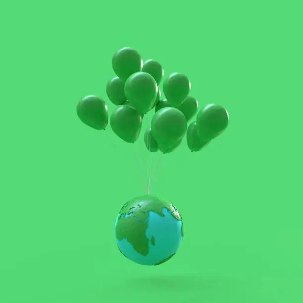Photo of Minimal idea concept. Floating earth with green balloons