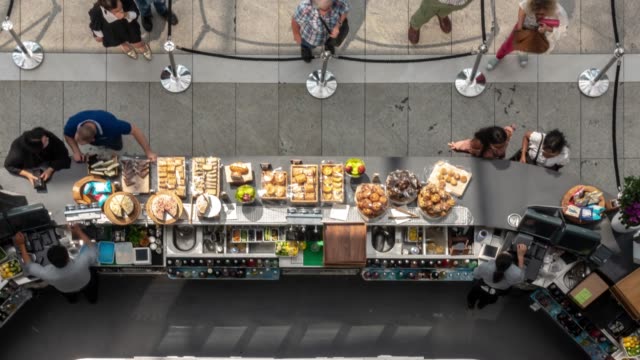 Aerial Time-lapse: customer buy food from bar kiosk in cafeteria