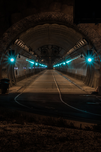 Highway Tunnel  in a city at night with green lights through tunnel. Road at entrance to tunnel