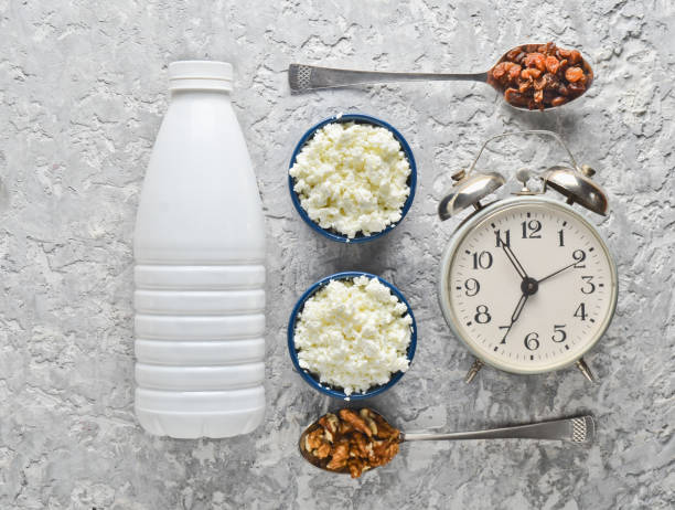 건강, 식이 음식입니다. 아침 조식입니다. 요구르트 병 그릇을 코 티 지 치즈, 호두와 건포도, 숟가락 회색 콘크리트 테이블에 알람 시계. 최고의 볼 수 있습니다. 평평 하다 음식 - nonfat milk 뉴스 사진 이미지