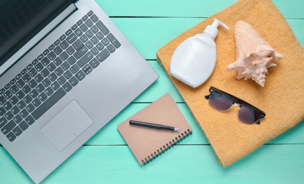istock Online work at a beach resort. Laptop, towel, notepad, sunglasses, shell, sunblock, top view, flat lay 1088876366