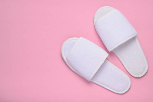 istock White hotel slippers on a pastel pink background, top view, minimalist trend 1088879936