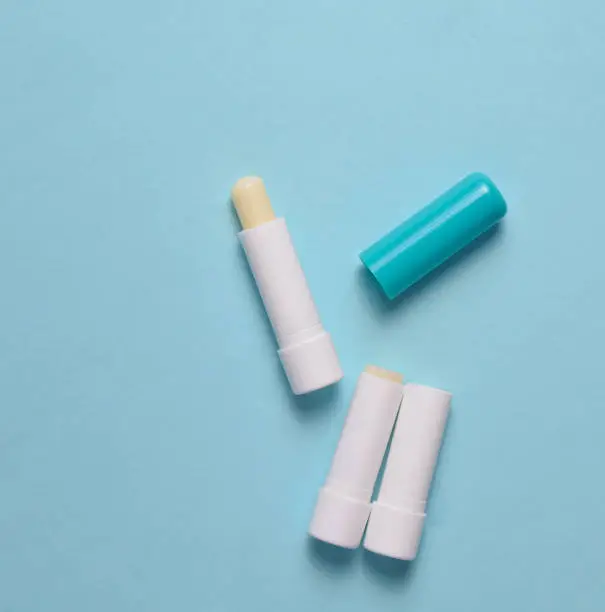 Hygienic lipstick on a blue pastel background, top view, minimalism
