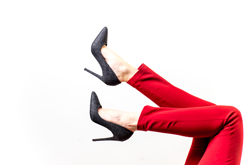 Female legs in red trousers and shoes on white background