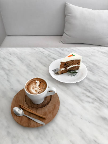 Top view of hot latte coffee and carrot cake on wooden tray on marble table