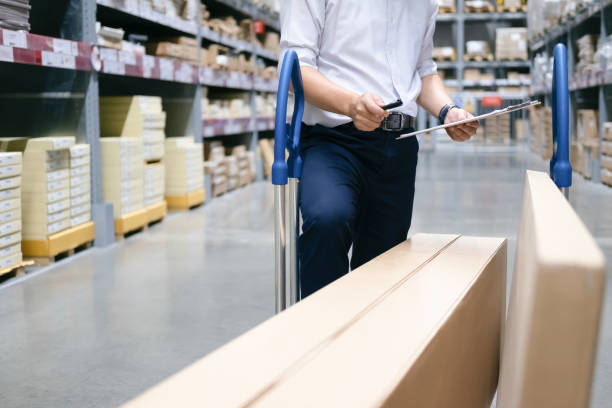 Warehouse worker checking goods at warehouse. Wholesale, logistic, business, export and people concept - Man warehouse worker checking goods at warehouse. portage valley stock pictures, royalty-free photos & images