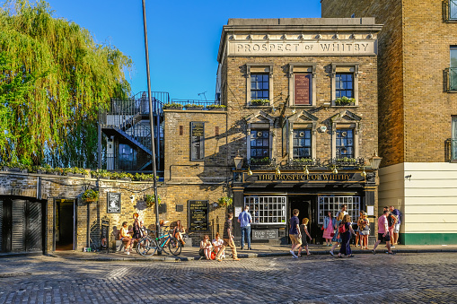 Wapping, London, UK - May 7, 2018: Horizontal shot of the Prospect of Whitby Pub in Wapping with people enjoying the sunshine outside. Afternoon shot with lovely light.