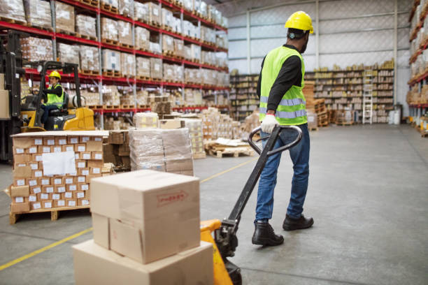 trabajador moviendo cajas en carretilla en almacén - carretilla industrial fotografías e imágenes de stock