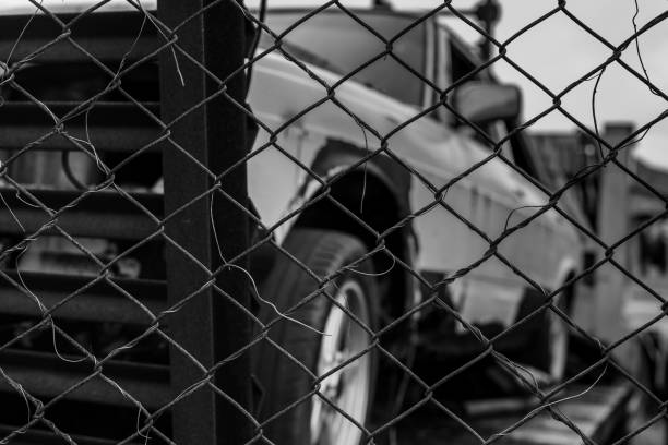 istock Old wrecked car in black and white scene. Abandoned rusty car in wire fence. Decayed abandoned truck. View from fence to truck. Tragedy and loss. Financial crunch and economic recession concept. 1088912538