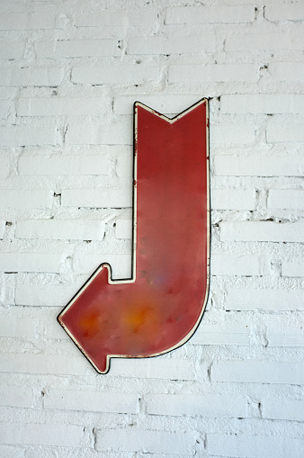 left arrow sign on white brick wall, block background with arrow sign