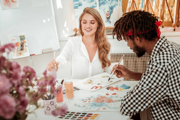 istock Appealing stylish art teacher feeling joyful painting with her student 1088920532