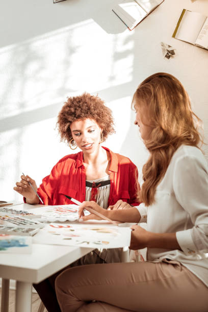 istock Two stylish appealing women speaking while drawing together 1088920574