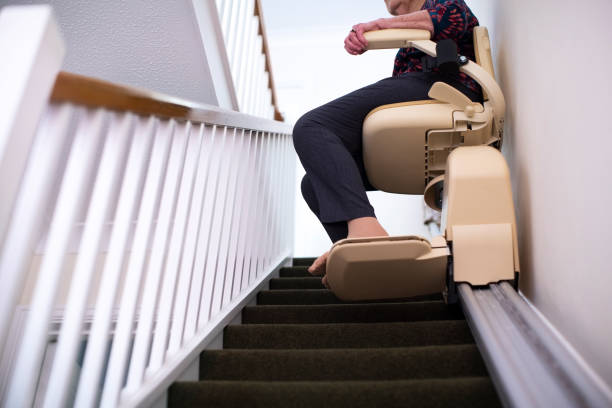 Detail Of Senior Woman Sitting On Stair Lift At Home To Help Mobility Detail Of Senior Woman Sitting On Stair Lift At Home To Help Mobility caution step stock pictures, royalty-free photos & images