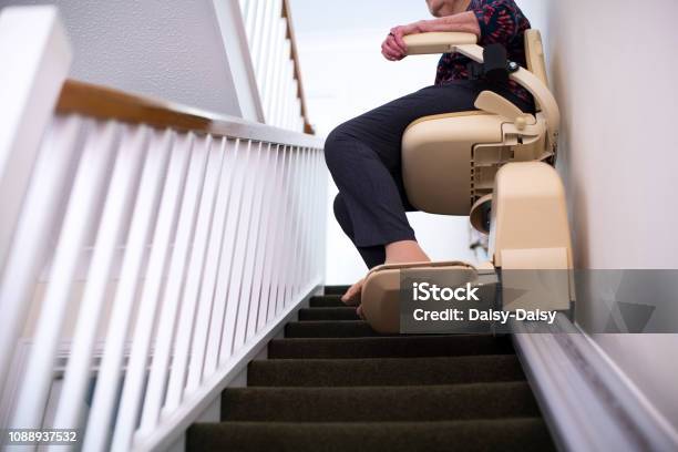 Detail Of Senior Woman Sitting On Stair Lift At Home To Help Mobility Stock Photo - Download Image Now