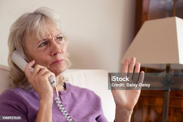 Senior Woman Receiving Unwanted Telephone Call At Home Stock Photo - Download Image Now