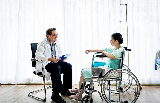 Doctor and patient with illness talking in hospital room