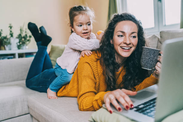 mother and daughter having fun online - lying down women laptop freedom imagens e fotografias de stock