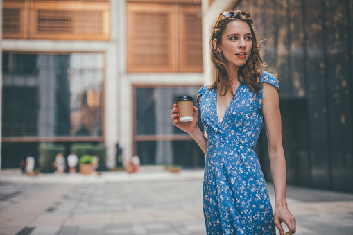 One woman, cute young woman in city, holding a coffee cup.