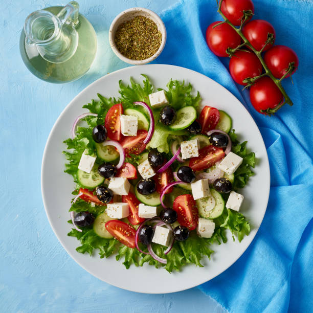 istock Greek salad on white plate on bright blue table, top view 1088952104